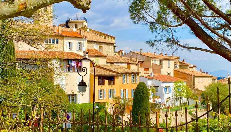 Bâtiments et jardins au toit de terre cuite à Mougins, en France, encadrés d'arbres et d'une clôture en fer forgé.
