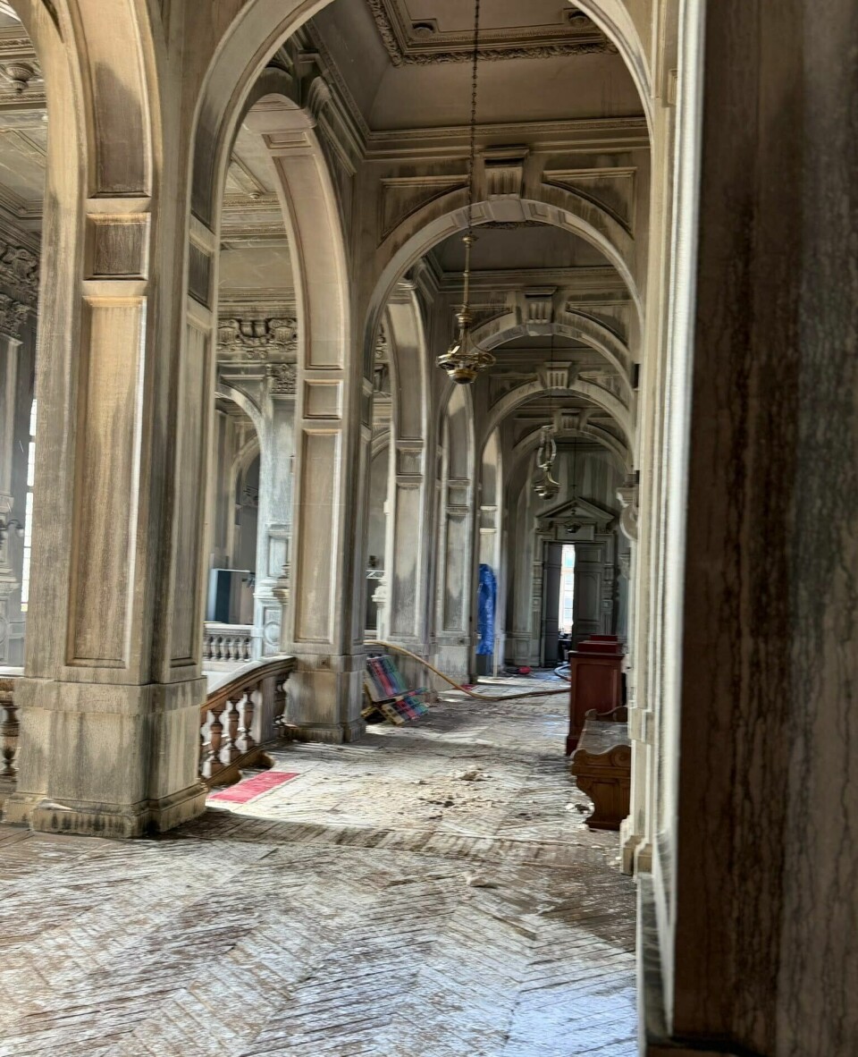 Colonnade en pierre ornée d'arcs, de colonnes et de sols à motifs menant à une porte éloignée